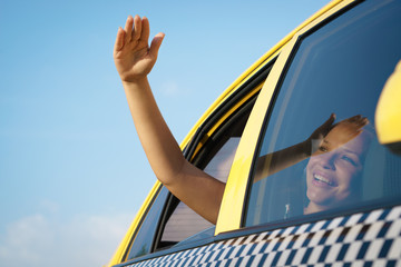 Naklejka premium woman in taxi waving hand out of car window