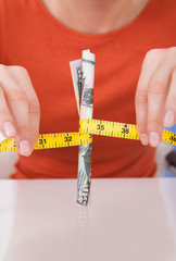 Woman Holding Measuring Tape Around 50 Dollar Bill