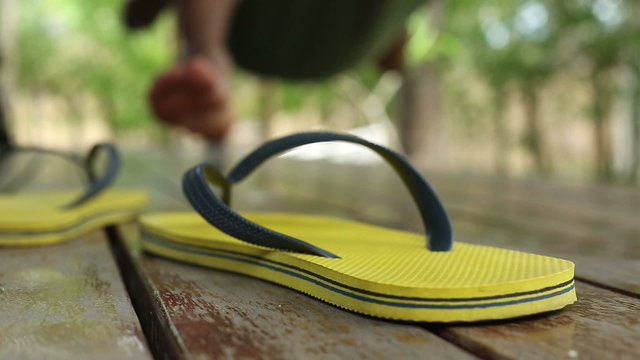 Foreground shot of a flip flop as a man swings in a hammock