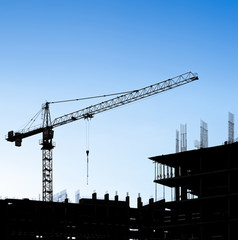 Silhouettes of a construction crane and building on a background