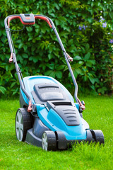 Fototapeta na wymiar blue lawn mower on green grass