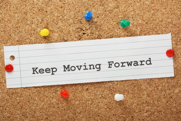 The phrase Keep Moving Forward on a cork notice board