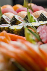 Close up side view of maki sushi on a platter with blurred sushi in foreground and backgound