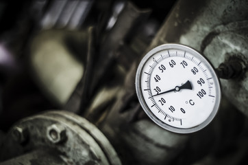 Industrial temperature gauge with out of focus pipes in background
