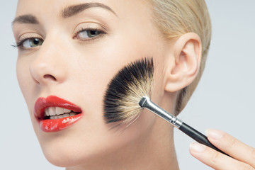 Beautiful Young Woman Applying Makeup with Brush