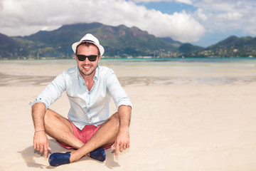 Fototapeta premium smiling young man sitting on the beach