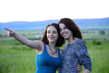 Beautiful young women in a field one of them points at something