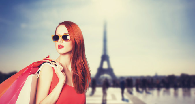 Redhead women with shopping bags on parisian background.