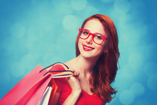 Redhead girl with shopping bags on blue background.