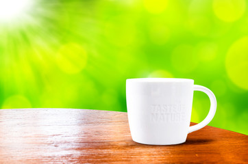 wood round table with white mug with green bokeh background