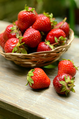 Ripe sweet strawberries in wicker basket on table in garden