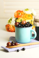 Ripe blackcurrants in mug and glass jar with tasty jam