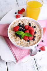 Tasty oatmeal with berries on table close-up