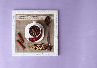 Wooden frame with white mug, coffee grains and spices