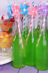 Bottles with drink and sweets on table on bright background