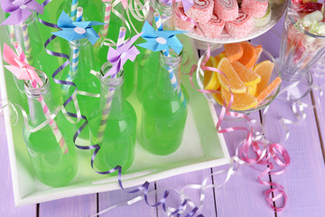 Bottles with drink and sweets on wooden background