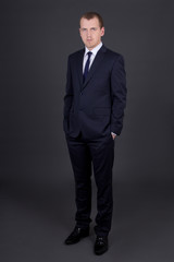 young business man in suit standing over grey