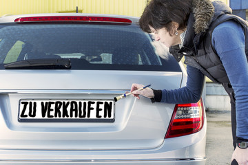 Woman writes with a brush on the sign of cars