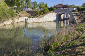Fototapeta na wymiar bridge over a river that runs between trees with reflections