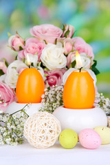 Easter candles with flowers on bright background