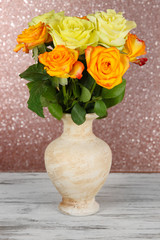 Beautiful bouquet of roses in vase on table on brown background