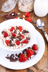 Healthy cereal in bowl with strawberries and chocolate