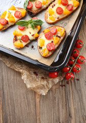 Tasty bruschetta with tomatoes on pan, on old wooden table