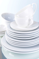 Set of white dishes on table on light background