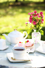 Coffee table with teacups and tasty cakes in garden