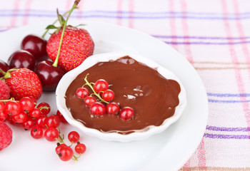 Ripe sweet berries and liquid chocolate on tablecloth