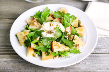Green salad with apples, walnuts and cheese on wooden