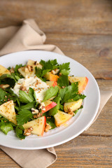 Green salad with apples, walnuts and cheese on wooden