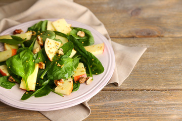 Green salad with apples, walnuts and cheese on wooden