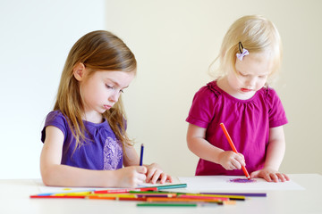 Two little sisters drawing with colorful pencils