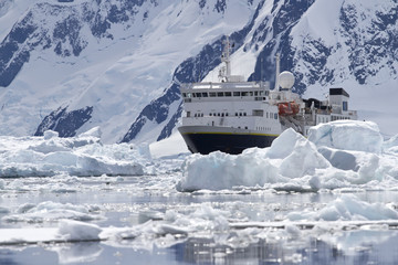 big blue tourist ship in the ice in the background of the Antarc