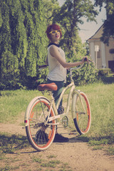 Obraz premium Hipster girl with her vintage bicycle, enjoying beautiful sunny