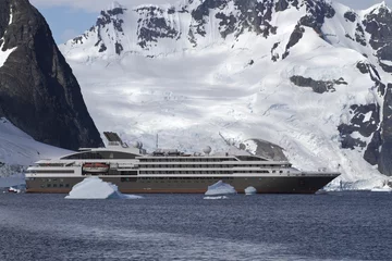 Fototapete Antarktis tourist liner sailing among icebergs in Antarctica on a backgrou