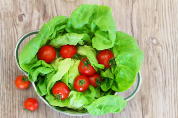 Green lettuce leaves in colander and cherry tomatoes