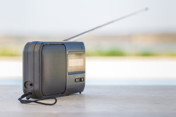 Small transistor radio with a string cord handle outside.