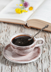 Cup of coffee and flowers on open book