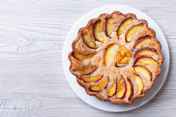 round peach pie on a wooden background top view