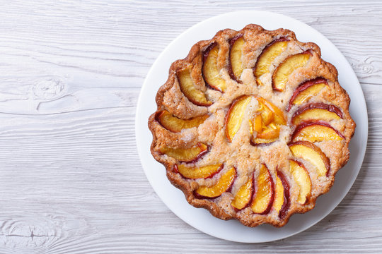 Round Peach Pie On A Wooden Background Top View