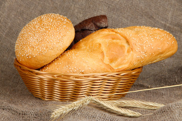 Baked bread in wicker basket on burlap background