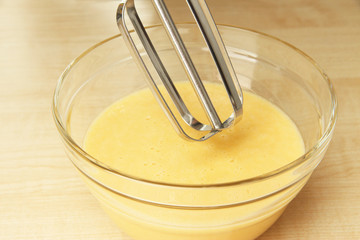 Cooking, whipping eggs with electric whisk in bowl, close up