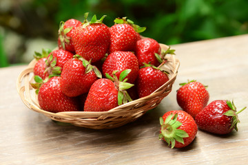 Ripe sweet strawberries in wicker basket on table in garden