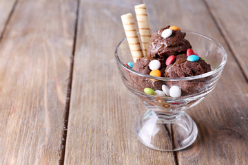 Chocolate ice cream with multicolor candies and wafer rolls in