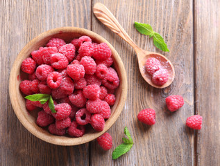 Ripe sweet raspberries in bowl on table close-up