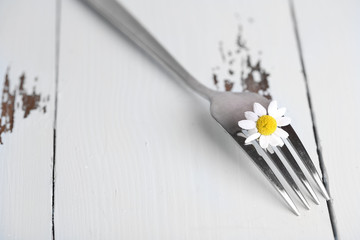 Fork with daisy flower, on wooden background