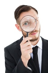 Fototapeta na wymiar Geeky businessman looking through magnifying glass
