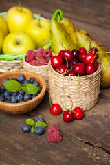 Fresh juicy apples, pears and berries on a wooden table